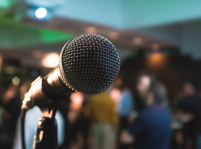 Stage microphone before an audience, representing English interpretation at global events
