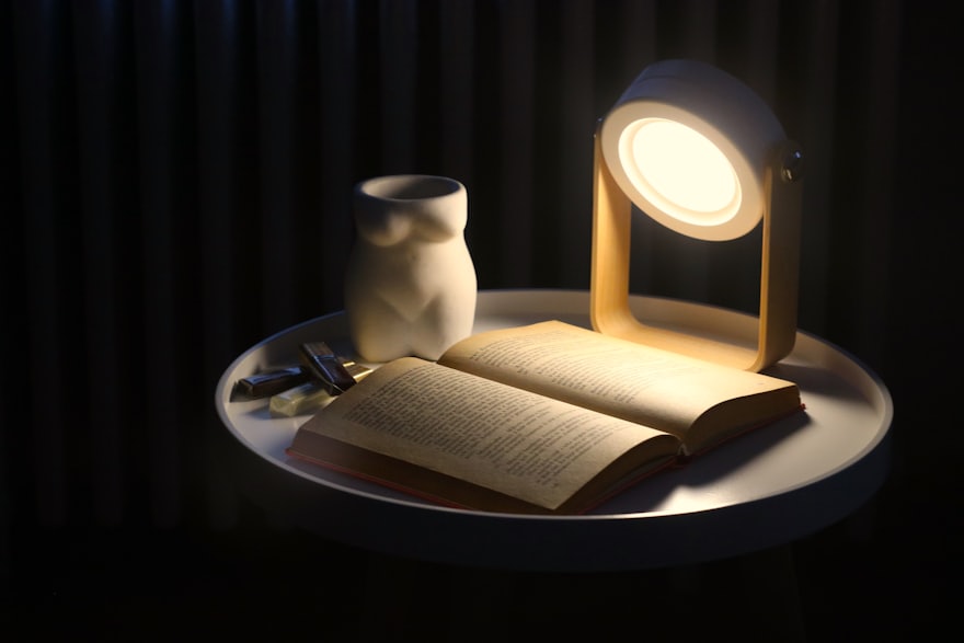 Open book beside a reading lamp on a writing desk