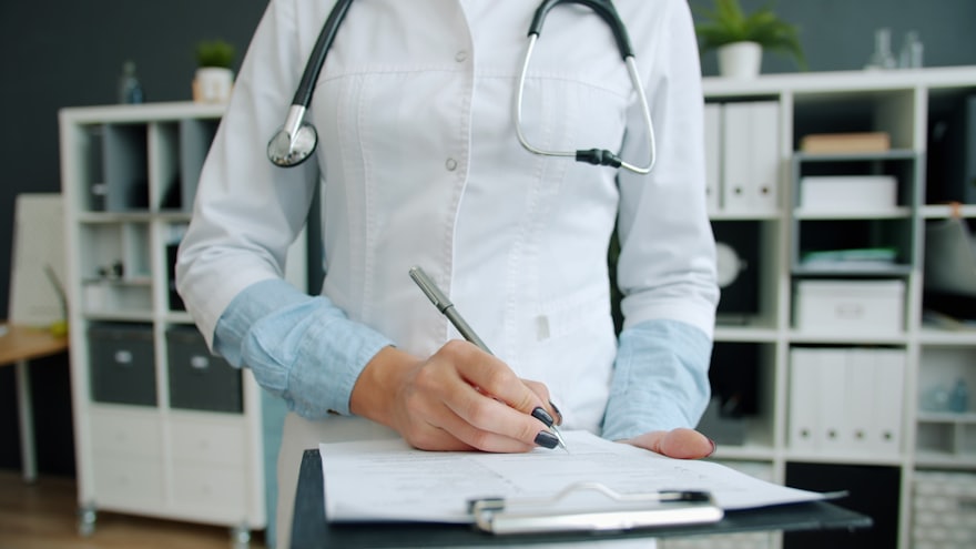 Physician completing medical records at a clinic desk